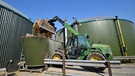 Ein Mann füllt mit einem Radlader Maissilage in eine Biogasanlage. | Bild: picture-alliance/dpa