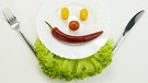 Ein Gesicht aus Gemüse ist auf einem Teller angerichtet: Zukünftig werden wir viel mehr Gemüse essen, wenn alle Menschen satt werden sollen. | Bild: picture alliance/Bildagentur-o
