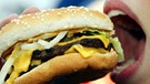 Eine junge Frau isst einen Hamburger. Laut Berechnungen der Forscher um Stephan Klasen von der Universität Göttingen wird sich der Kalorienbedarf bis 2100 um bis zu 80 Prozent erhöhen. | Bild: dpa-Bildfunk/Fotograf: Gero Breloer