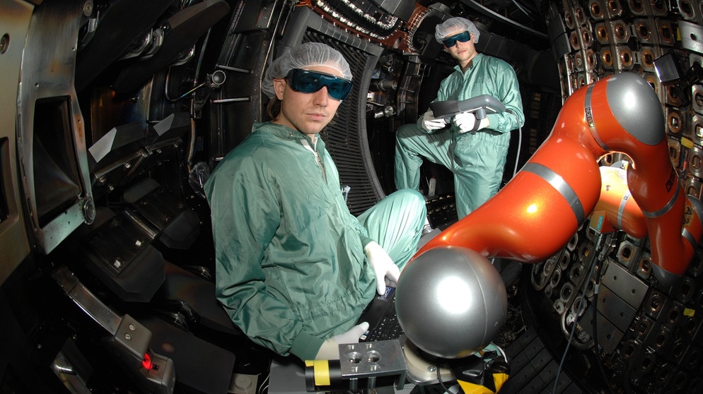 In der Forschungsanlage Asdex UPGRADE findet eine Lasermessung statt, zwei Menschen befinden sich im leeren Plasmagefäß. | Bild: IPP, Volker Rohde