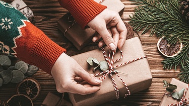 Eine Frau packt Geschenke ein.  | Bild: picture-alliance/dpa