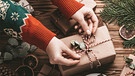 Eine Frau packt Geschenke ein.  | Bild: picture-alliance/dpa