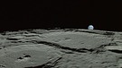 Mondoberfläche mit Erduntergang. Unter der grauen, mit Kratern übersäten und mit dickem Mondstaub bedeckten Oberfläche des Mondes ist einiges los: Unser Trabant ist kein toter Klumpen Gestein. Mondbeben rumoren und seine Kruste gibt bis heute Rätsel auf. | Bild: JAXA