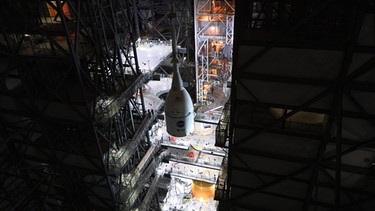 Die Raumkapsel Orion wird auf der Rakete SLS montiert. Im November 2022 startete die unbemannte Mondmission Artemis 1 zum Mond. Knapp eine Woche später flog die Raumkapsel Orion dicht an dessen Oberfläche vorbei - und landete im Dezember wieder auf der Erde. Hier erfahrt ihr mehr über die Artemis-Mission.  | Bild: NASA/Chad Siwik