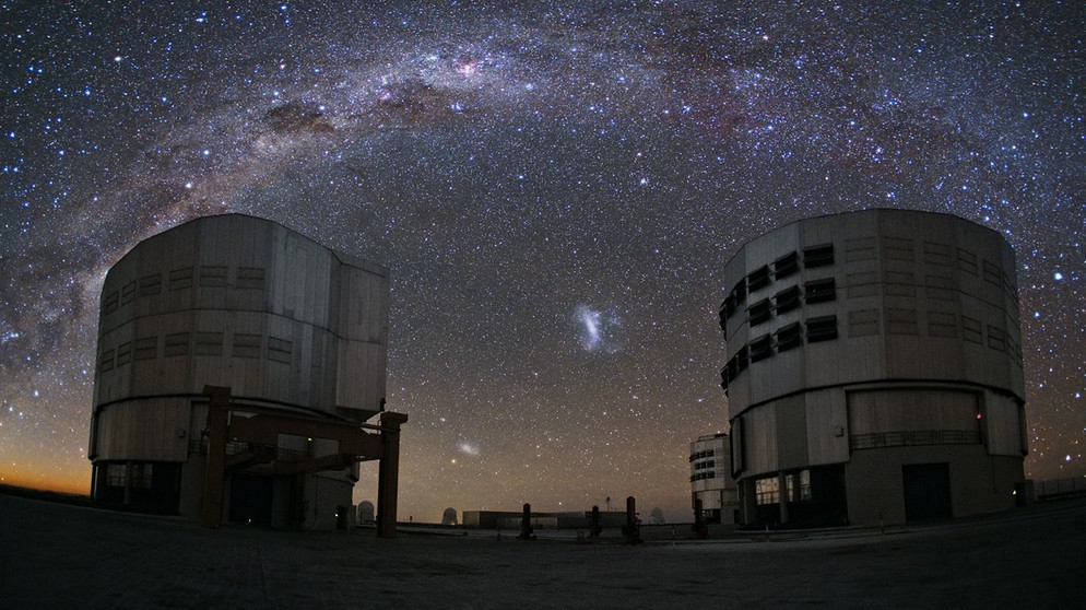 Auf der Spitze des Cerro Paranal hoch über der Atacama Wüste in Chile sitzend, aalen sich zwei der Einheiten des Very Large Telescope im Sternenlicht und beobachten dabei die Milchstrasse, die sich wie eine Brücke über das Paranal-Observatorium der ESO hinzieht. | Bild: ESO/Y. Beletsky
