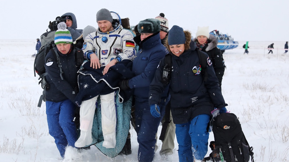 Astronaut Alexander Gerst wird am 20. Dezember 2018 nach der Landung von Mitgliedern des Bergungsteams getragen. Nach über einem halben Jahr in der Schwerelosigkeit auf der Raumstation ISS kann der Astronaut nicht mehr selbst gehen. Sein Körper muss sich erst wieder an die Schwerkraft gewöhnen. | Bild: picture-alliance