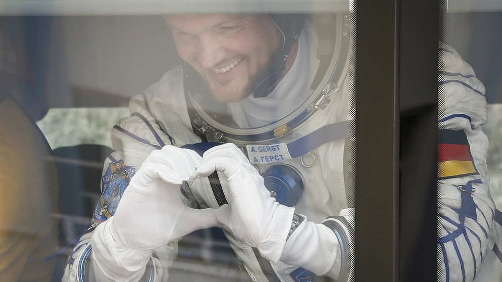 Alexander Gerst formt mit seinen Händen ein Herz an Bord des Busses, der den deutschen Astronauten zur Startrampe bringt. | Bild: dpa-Bildfunk/Shamil Zhumatov