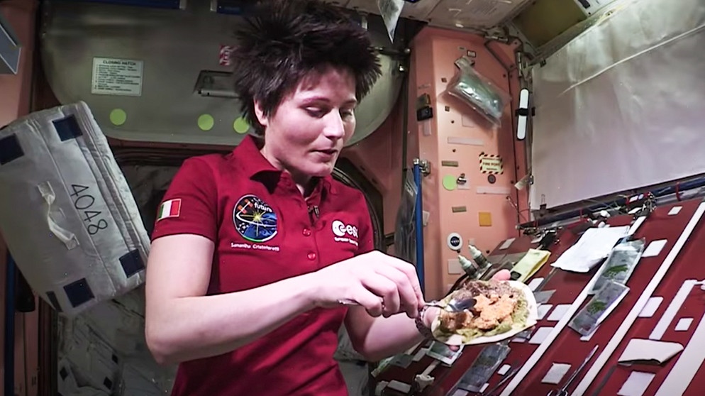 Die italienische Astronautin Samantha Cristoforetti streicht in der ISS-Küche Essen auf eine Tortilla. | Bild: ESA auf Youtube