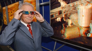 Sigmund Jähn mit einer 3D-Brille vor einem ISS-Bild. Der ehemalige Kosmonaut der DDR bleibt ein begeisterter Weltraum-Fan. | Bild: picture-alliance/dpa