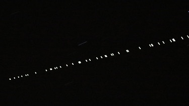 Eine Kette von Starlink-Satelliten des US-amerikanischen Unternehmens SpaceX zieht am 23. Arpil 2020 über den Himmel.  | Bild: picture-alliance / Promediafoto / Michael Deines 
