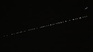 Eine Kette von Starlink-Satelliten des US-amerikanischen Unternehmens SpaceX zieht am 23. Arpil 2020 über den Himmel.  | Bild: picture-alliance / Promediafoto / Michael Deines 