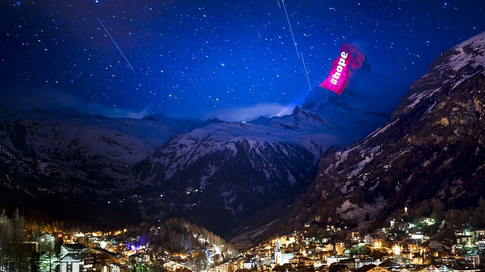 Der Schweizer Lichtkünstler Gerry Hofstetter illuminierte das Matterhorn im März 2020. Auch mit auf dem Bild: Die helle Kette aus Satelliten des Projekts Starlink.
| Bild: picture alliance/KEYSTONE | VALENTIN FLAURAUD