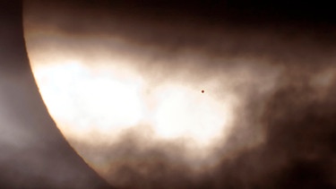 Merkur vor der Sonne, halb von Wolken verdeckt: Dieses Bild machte David Cortner während des Merkurtransits am 8. November 2006 (in Europa nicht zu sehen). Merkur ist so winzig, dass er nicht mit bloßem Auge vor der Sonne zu sehen ist. Erst mit kleineren Teleskopen kann man den Merkurtransit beobachten. Teleskope wie Kameras müssen mit speziellen Schutzfolien ausgerüstet sein. | Bild: David Cortner