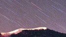 Leoniden-Sternschnuppen im November 1998 über der Chinesischen Mauer. Dieser Meteor-Strom bringt manchmal unzählige Sternschnuppen zu seinem Höhepunkt mit sich. | Bild: picture-alliance/dpa