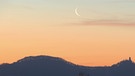 Abnehmende, sehr dünne Mondsichel am frühen Morgen über dem Siebengebirge im Rheinland | Bild: Rüdiger Balhar