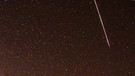 Ein Meteor des Perseiden-Sternschnuppen-Regens neben der Milchstraße am Sternenhimmel im August | Bild: Trix Pulfer