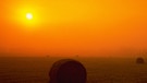 herbstliche Sonne kurz vor Sonnenuntergang über einer Wiese mit einem Heuballen | Bild: Photosphere