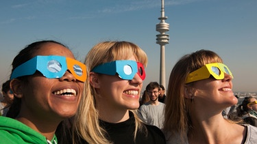 Drei junge Frauen mit Sonnenfinsternis-Brillen in München bei der Sonnenfinsternis im März 2015. Blicken Sie niemals ungeschützt in die Sonne, sonst riskieren Sie schwere Augenverletzungen bis zur Erblindung! | Bild: picture alliance / dpa | Andreas Gebert