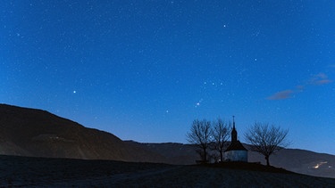 Der ganz helle Stern links im Bild ist Sirius und vom Sternbild Orion erkennt man rechts über dem Horizont den Gürtel des Jägers mit dem Schwert (über den Bäumen links). | Bild: Norbert Scantamburlo